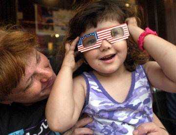 Angela Voss, 4, put on patriotic glasses distributed at Libertyfest on Main Street Monday night, where she and her mother, Connie Voss, arrived early to ... - 1040916-L